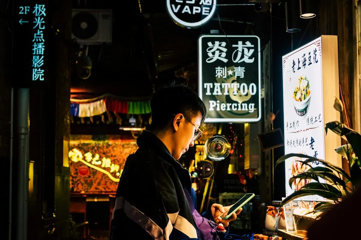 Traveller checking their phone on a Shanghai street at night